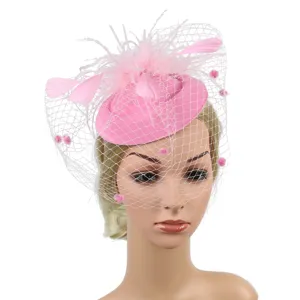 Pink feather fascinator hat with veil and pom poms, elegant bridal party headwear accessories.