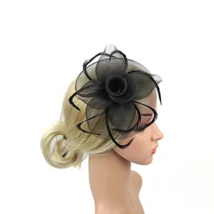 Détail de fascinateur en résille noire et plumes avec design floral délicat et voile pour fête femme.