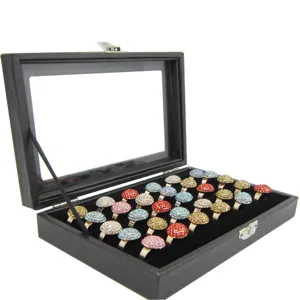 Black velvet ring display box with transparent lid and colorful rhinestone rings.