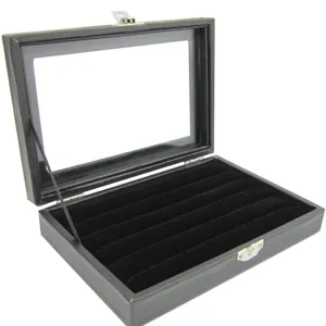 Black velvet jewelry display box detail showing ring slots and clear glass lid interior.
