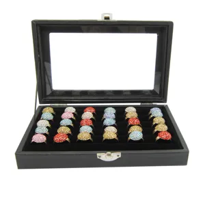 Detail view of black velvet jewelry display box showing colorful rhinestone rings inside.