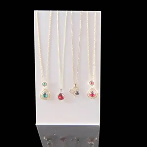 Gold chain necklace set with colorful teardrop crystal pendants on white display stand