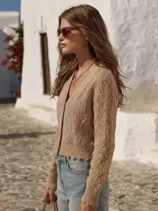 Detailed view of women's beige knit cardigan with textured cable pattern and raw hem trim.