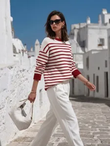 Detail shot of a casual striped knit top featuring contrast cuffs and crewneck design outdoors.