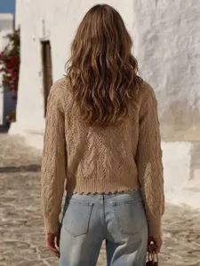 Detail view of a women cable knit cropped cardigan in vacation style, worn with blue jeans.
