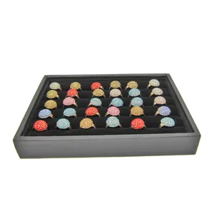 Close-up detail of colorful rhinestone ball rings neatly arranged on a professional black tray.