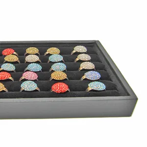 Close-up view of colorful crystal rhinestone cluster rings neatly arranged on a black velvet display tray.