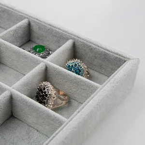 Detailansicht des eisgrauen Samt-Schmucktabletts mit mehreren Fächern und funkelnden Ringen.