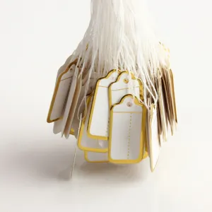 Blank white paper price tags with gold border and hanging strings detail view for jewelry retail.
