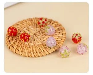 Close-up detail of handmade glass strawberry beads for DIY jewelry and phone charms making.