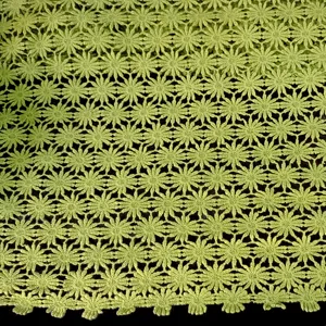 Vista di dettaglio del tessuto ricamato in cotone verde con motivo a fiori di prugno.