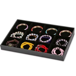 Close-up detail of black velvet jewelry display tray with neatly organized assorted bracelets.