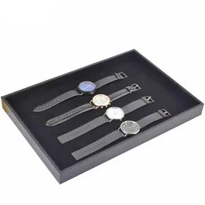 Black velvet watch display tray with four classic wristwatches for store showcase.