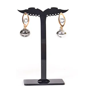 Detalle cercano de pendientes elegantes en tonos dorados y plateados en un soporte negro.