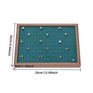 Detail view of the wooden ring display tray with green velvet lining and slot organization.