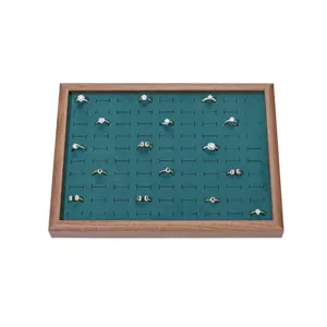 Wooden jewelry display tray with green velvet insert and multiple ring slots for ring storage.