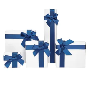 White gift boxes set with elegant blue satin ribbons for jewelry, necklace, ring packaging.