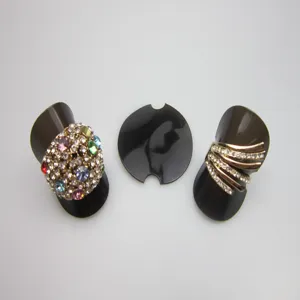 Vue détaillée de supports de bague en plastique noir avec des strass et des bandes métalliques.