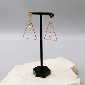 Gold-tone geometric triangle pearl drop earrings on display stand. Elegant design.