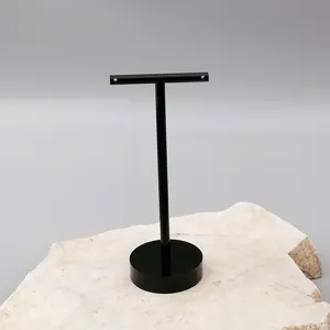 Detail view of a black acrylic T-shaped earring display stand on a stone prop, ideal jewelry holder.