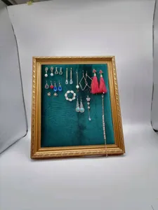 Close-up detail of the retro green velvet photo frame jewelry display board with various earrings.
