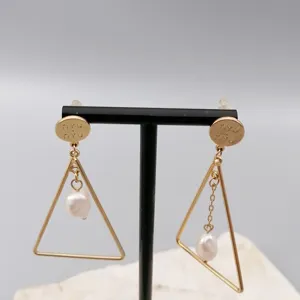 Gold triangle pearl earrings detail closeup with unique geometric metal design and pearl pendants.