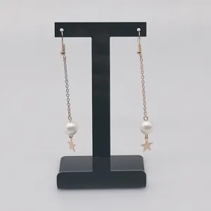 Gros plan détaillé de longues boucles d'oreilles à chaîne avec perle et pendentif étoile.