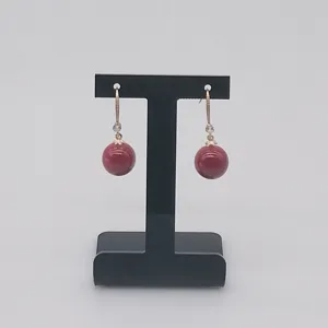 Élégantes boucles d'oreilles boules rouges présentées sur un support en T noir élégant.