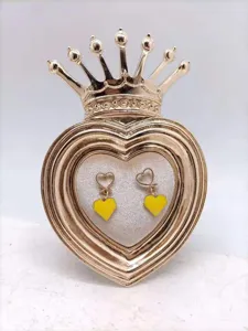 Gedetailleerd weergave van stijlvolle goudkleurige hart oorbellen met gele emaillen hangers.