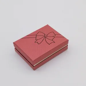 Close-up detail of a red textured gift box with black bow print, ideal for jewelry packaging.