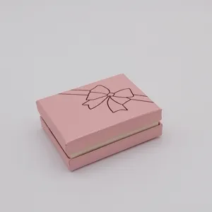 Pink cardboard jewelry gift box detail, rectangular packaging box with printed bow design.