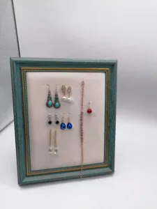 Vintage dark green picture frame jewelry display board with various earrings and necklace.