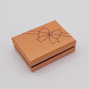 Orange jewelry gift box detail showcasing textured paper surface and elegant bow print design.