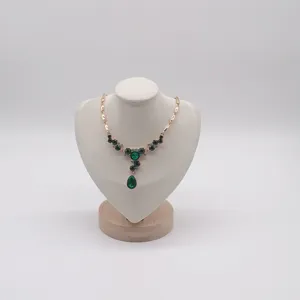 Detailed view of exquisite green crystal pendant necklace on jewelry display mannequin bust.