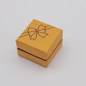 Detailed view of compact gold square jewelry gift box with elegant ribbon bow print packaging.