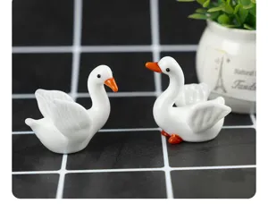 Close-up detail of cute handmade white glass goose figurines, charming desktop decor for display.