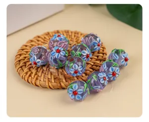 Close-up of purple lampwork glass beads with blue floral patterns for DIY jewelry making.