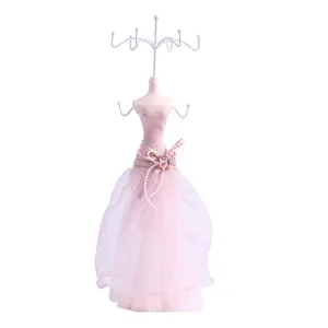 Pink dress jewelry display stand with metal hooks for necklaces, bracelets, and earrings.