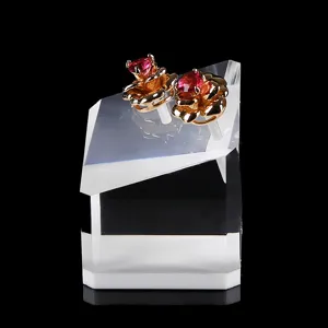 Gold tone red gemstone flower earrings displayed on clear acrylic stand for elegant jewelry look.