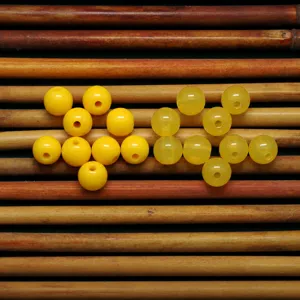 Primer plano de cuentas redondas de plástico amarillo, abalorios acrílicos artesanales.