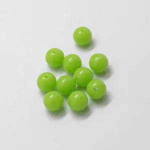 Dettaglio di perline rotonde in acrilico verde, superficie liscia con foro per bigiotteria.