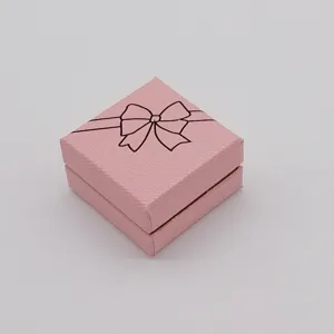 Close-up detail of a pink square jewelry gift box featuring a cute black bow print design.