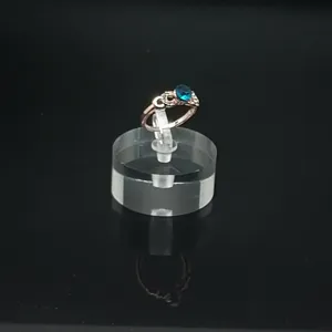 Gros plan détaillé d'une bague en cristal bleu scintillant sur support acrylique.