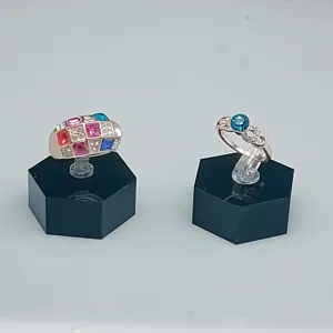 Vue détaillée de deux bagues tendance avec cristaux colorés et design géométrique sur socles.