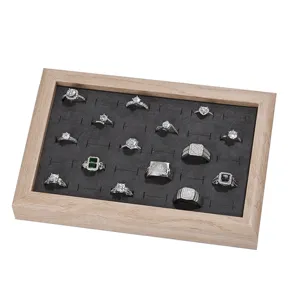 Solid wood jewelry display tray featuring dark velvet slotted pad with various shiny rings.