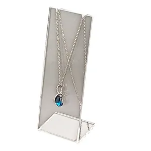 Collar de plata con colgante de cristal en gota azul expuesto en soporte acrílico transparente.