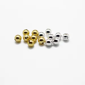 Gros plan de perles rondes dorées et argentées lisses avec trous pour bijoux DIY.