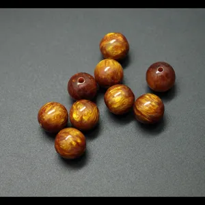 Close-up of golden silk resin beads detail, showing glossy surface and texture pattern.