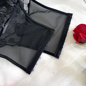 Dettaglio top corsetto in rete di pizzo nero con ricamo floreale e chiusura a gancio.