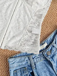 Weißes Spitzen-Bustier-Korsett-Detail kombiniert mit blauen Jeansshorts Flatlay Nahaufnahme.